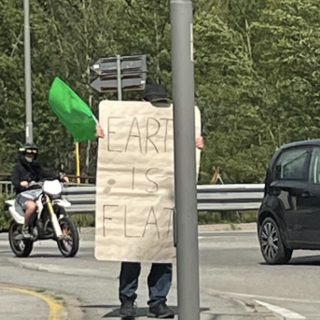 Terrapiattista solitario manifesta con un cartello di fronte all'Eurospin di Domo
