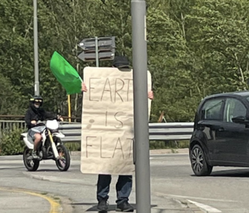 Terrapiattista solitario manifesta con un cartello di fronte all'Eurospin di Domo