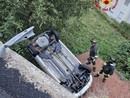 Auto esce di strada e si ribalta sul tetto di una legnaia