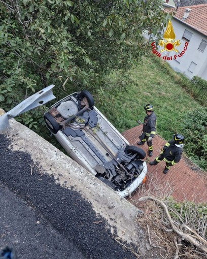 Auto esce di strada e si ribalta sul tetto di una legnaia